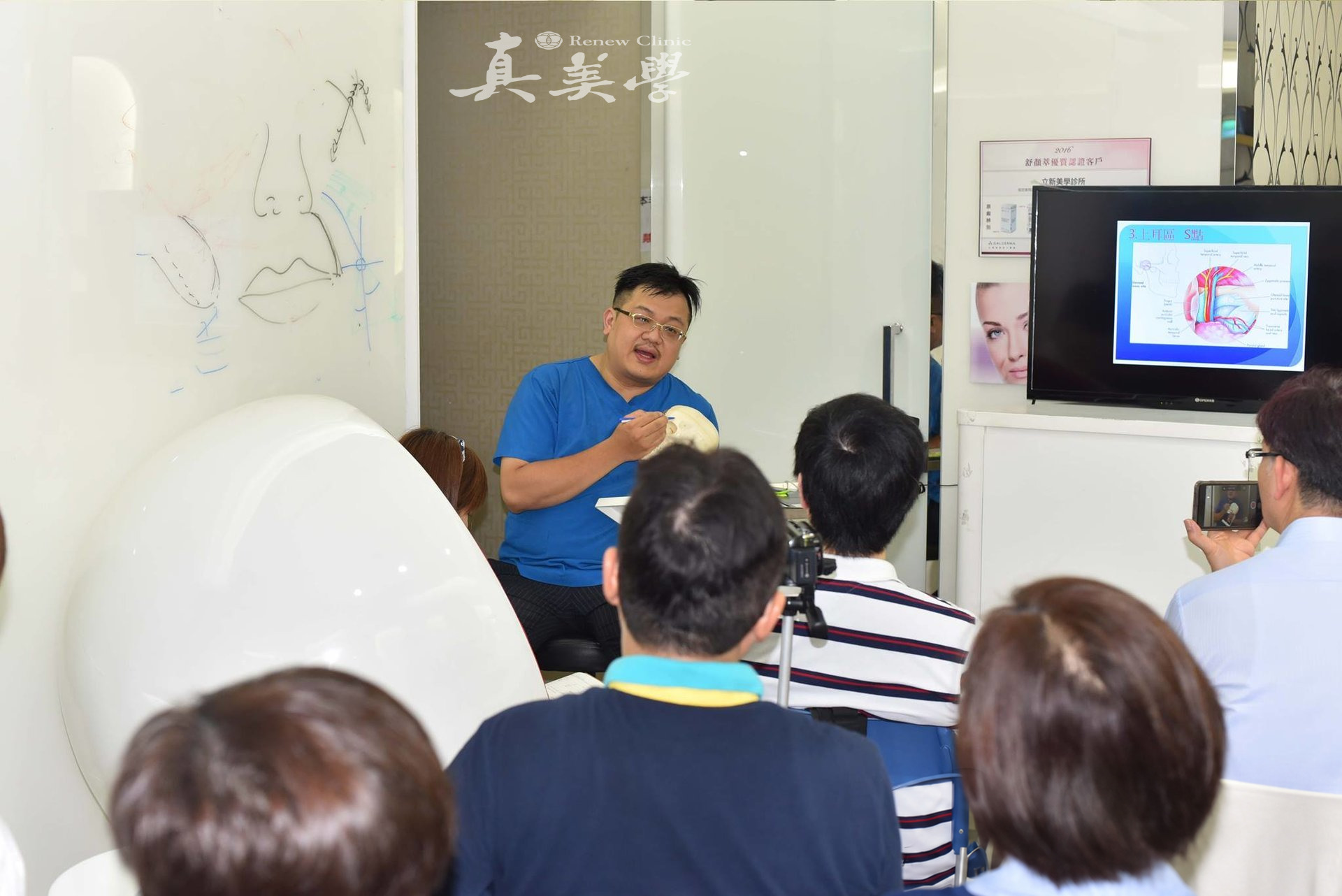 張光正醫師手持頭骨模型向成人醫師學員講解面部結構