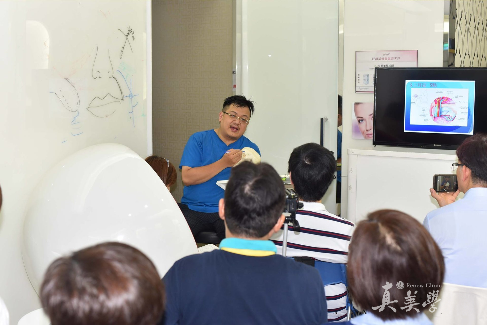 張光正醫師手持頭骨模型向成人醫師學員講解面部結構